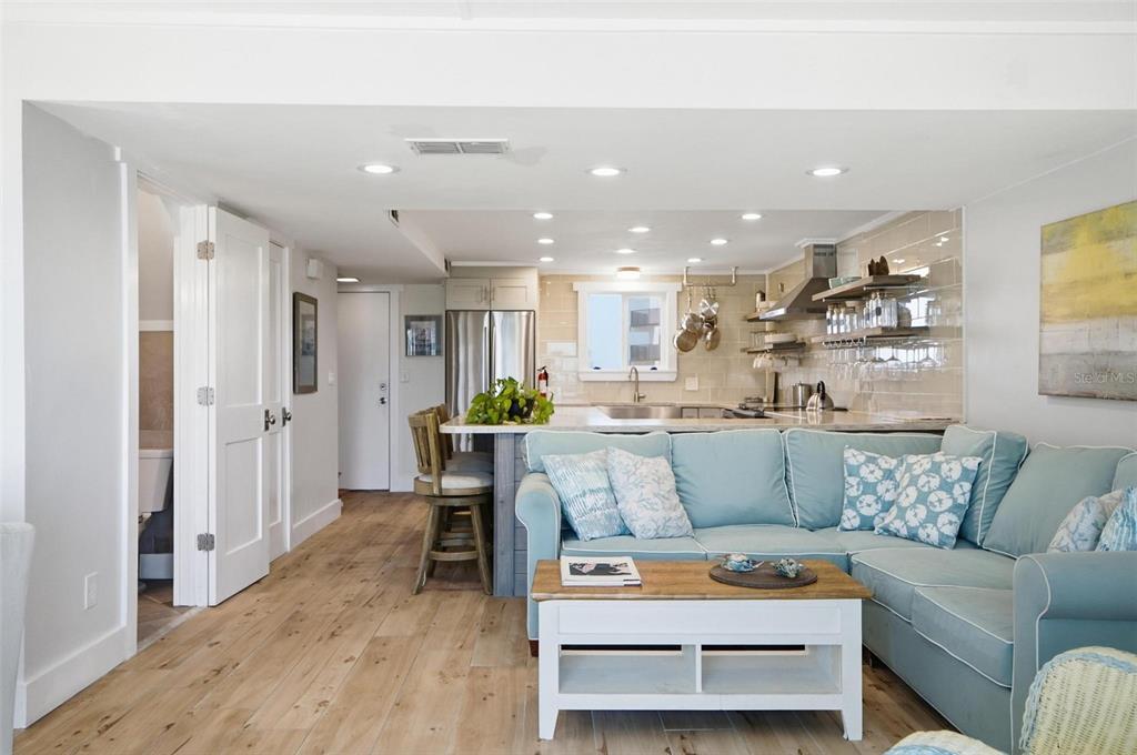 A light-filled open-concept living room and kitchen featuring light wood floors and blue furniture — 3510 S OCEAN SHORE BOULEVARD UNIT 217, FLAGLER BEACH, FL