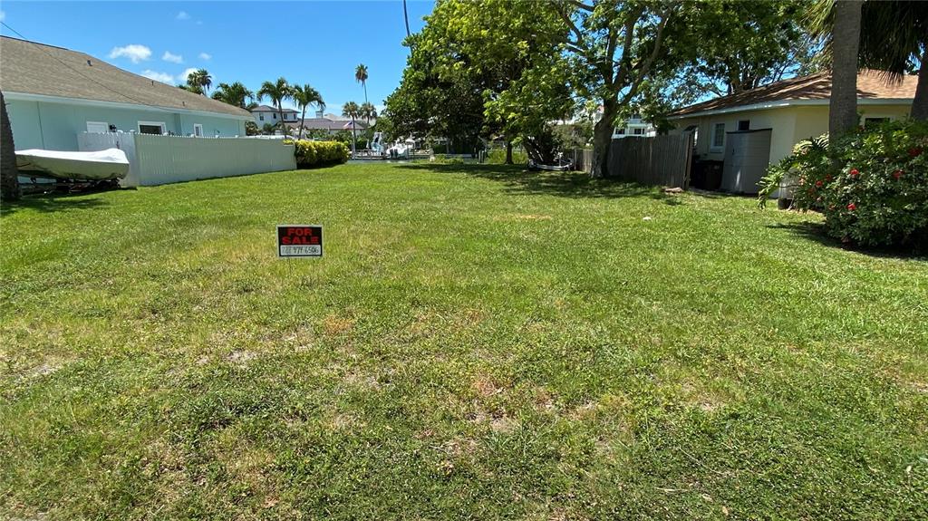 A grassy vacant lot sits between two houses with a for sale sign in the foreground — 321 12TH AVENUE, INDIAN ROCKS BEACH, FL
