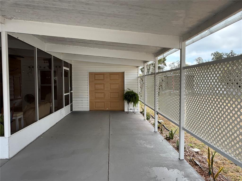 A covered concrete patio features a white lattice privacy screen and a wooden door — 50 N BOBWHITE ROAD, WILDWOOD, FL