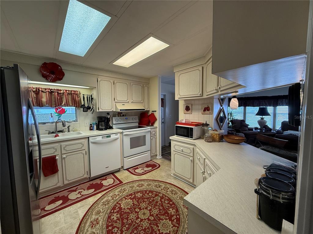 A kitchen features white cabinets, white appliances, a patterned area rug, and recessed lighting — 50 N BOBWHITE ROAD, WILDWOOD, FL