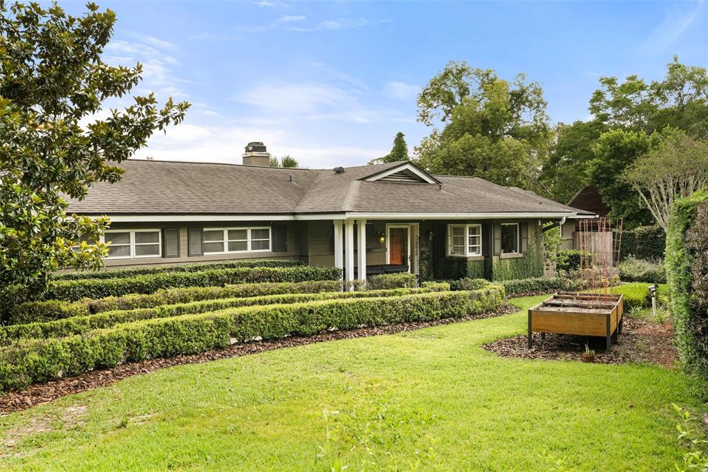 A single-story house with dark siding, a shingled roof, and manicured hedges in the yard — 119 HOLLIE COURT, MAITLAND, FL