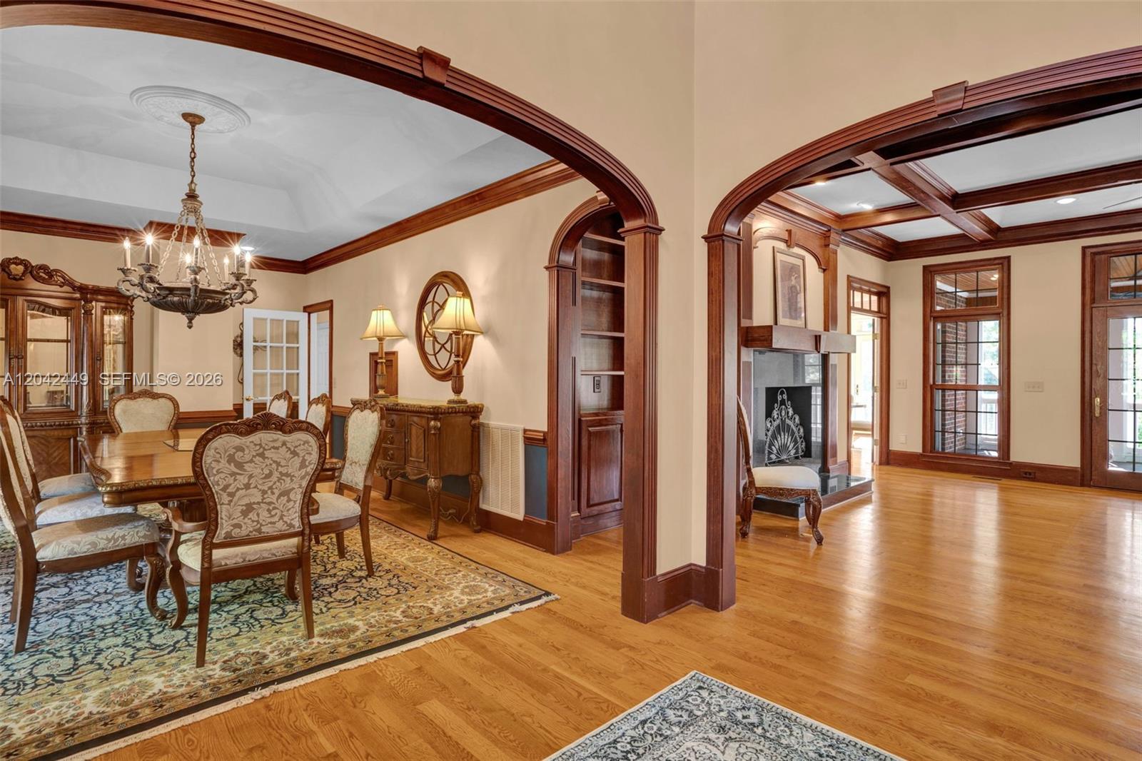 A formal dining room and adjacent living area feature hardwood floors, arched doorways, and woodwork — 2579 Grey Rabbit Run, NC 27205, NC