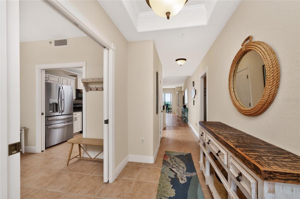 A hallway features tile flooring, a rustic console table, a rope mirror, and a kitchen entrance — 167 TAMPA AVENUE E UNIT 513, VENICE, FL