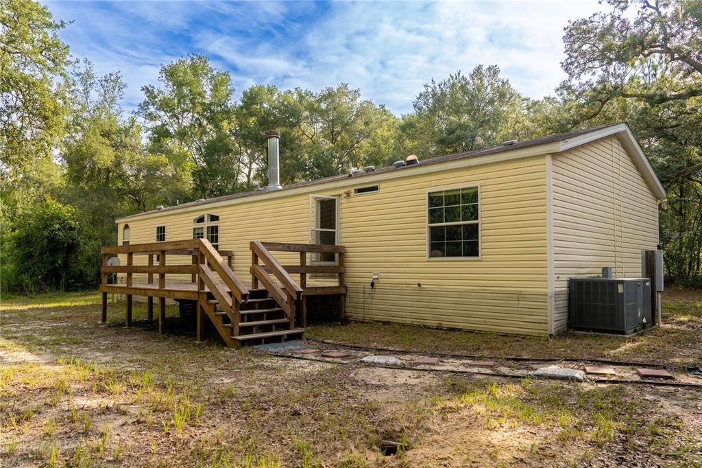 A yellow mobile home with a wooden deck and an outdoor HVAC unit in a yard — 11934 CR 656H, WEBSTER, FL