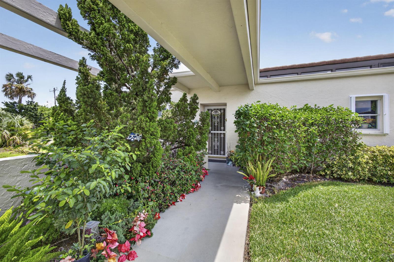 A concrete walkway leads to a front door sheltered by a modern architectural overhang — 2651 Boundbrook Boulevard # 110, West Palm Beach FL 33461, WEST PALM BEACH, FL