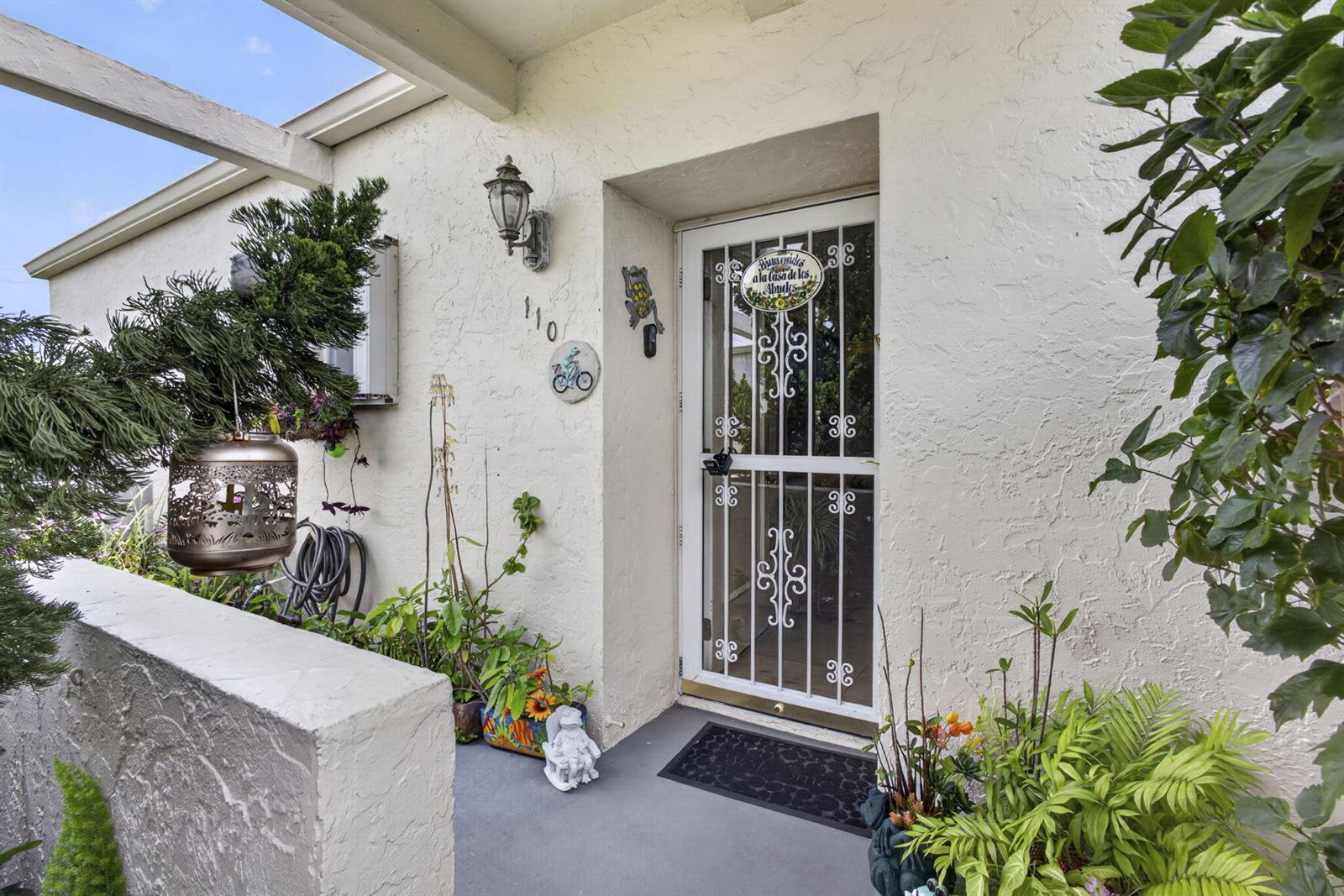 A white stucco home entrance features a decorative security door, potted plants, and house number — 2651 Boundbrook Boulevard # 110, West Palm Beach FL 33461, WEST PALM BEACH, FL