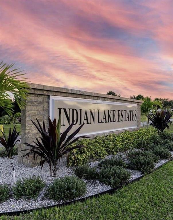 A stone monument sign for Indian Lake Estates stands in a landscaped garden at sunset — 13 INDIAN LAKE DRIVE, INDIAN LAKE ESTATES, FL