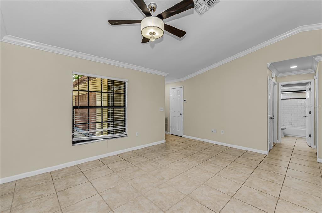 A room with beige walls, tile flooring, a ceiling fan, and a view into a bathroom — 260 ARBOR GLEN DRIVE, PALM HARBOR, FL