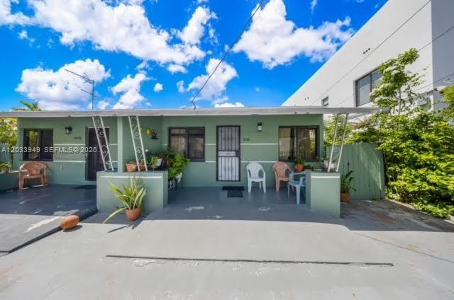 A single-story green house with a flat roof, a front porch, and a paved driveway — MIAMI, FL