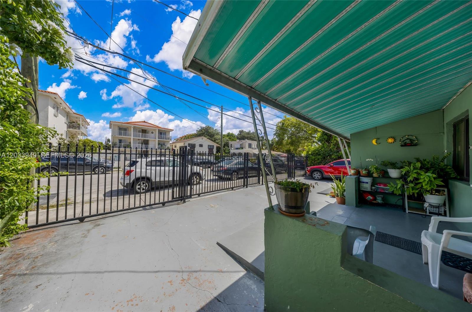 A paved driveway leads to a covered porch with green walls and a metal awning — MIAMI, FL