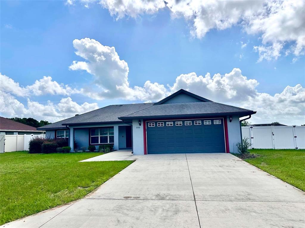 A single-story house with a blue exterior, a two-car garage, and a concrete driveway — 999 SE 69TH AVENUE, OCALA, FL