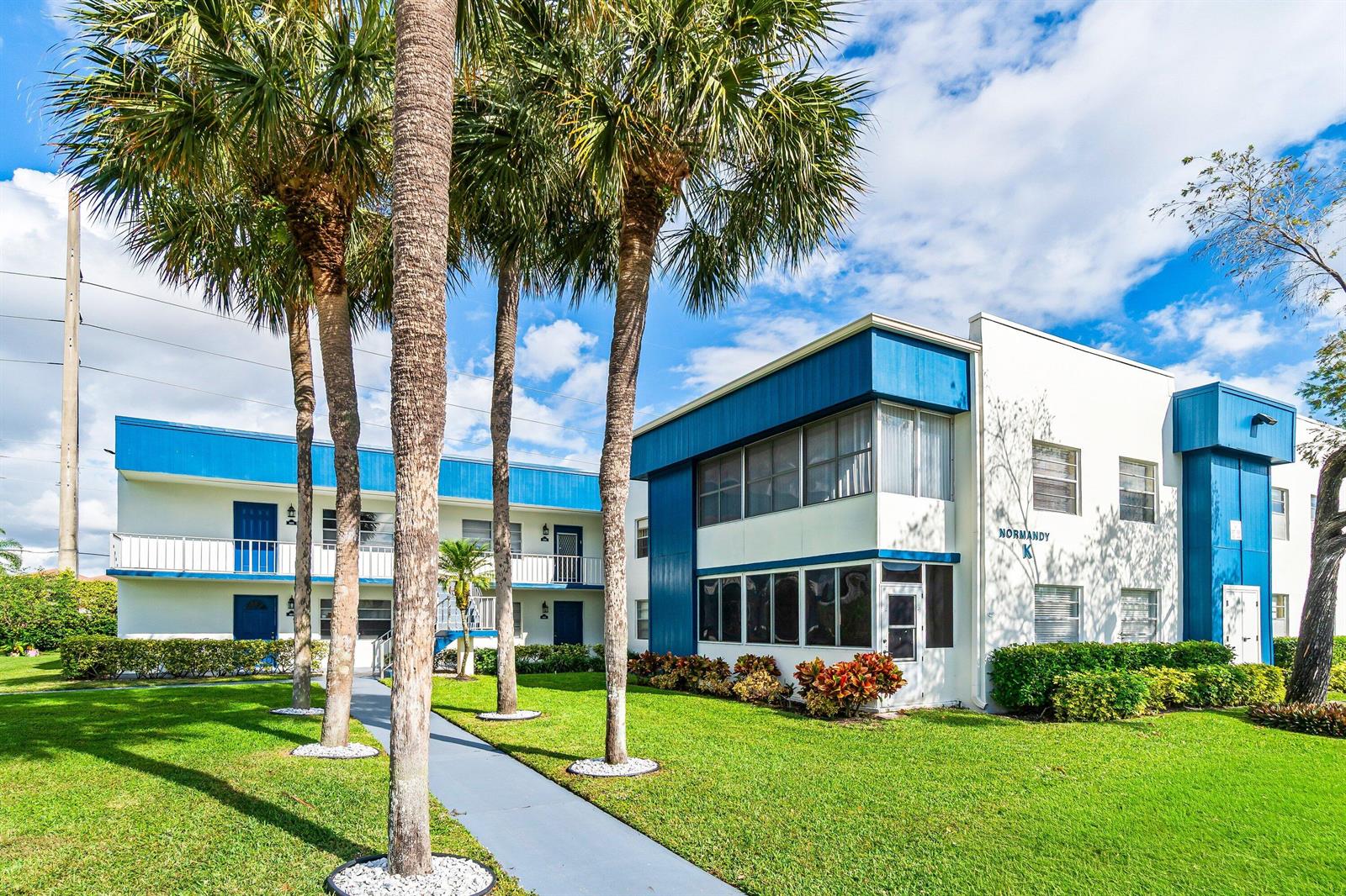 A two-story apartment building with blue accents, palm trees, and a walkway on the lawn — 508 Normandy K # 508, Delray Beach FL 33484, DELRAY BEACH, FL