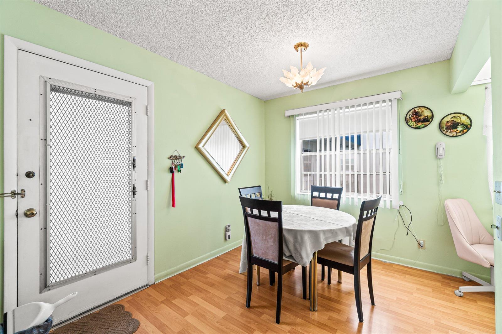 A dining area features light green walls, wood-look flooring, a round table, and a chandelier — 508 Normandy K # 508, Delray Beach FL 33484, DELRAY BEACH, FL
