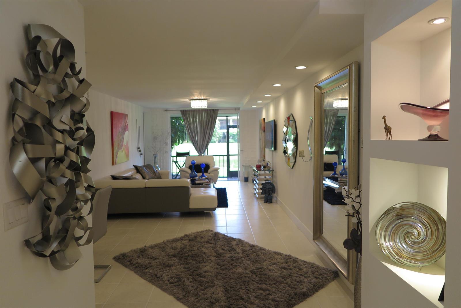 A living room features a large mirror, a shag rug, and recessed shelving with decorative objects — 7875 La Mirada Drive, Boca Raton FL 33433, BOCA RATON, FL