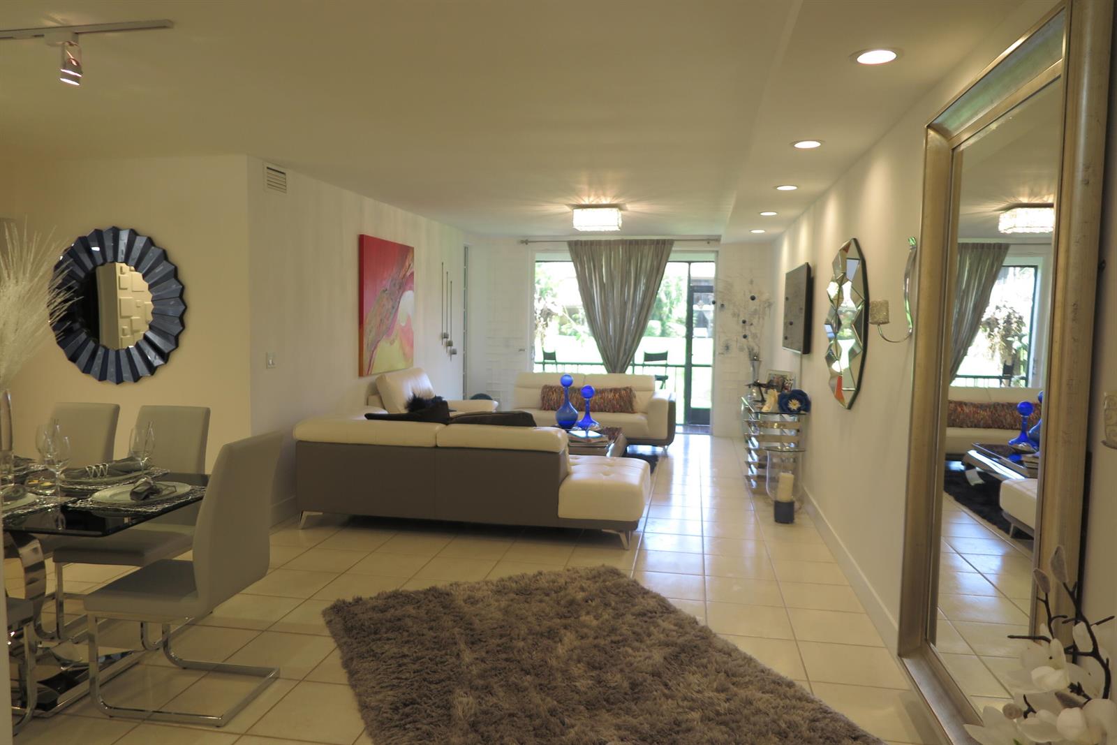 A living and dining area features white tile floors, a gray sectional, and a large mirror — 7875 La Mirada Drive, Boca Raton FL 33433, BOCA RATON, FL