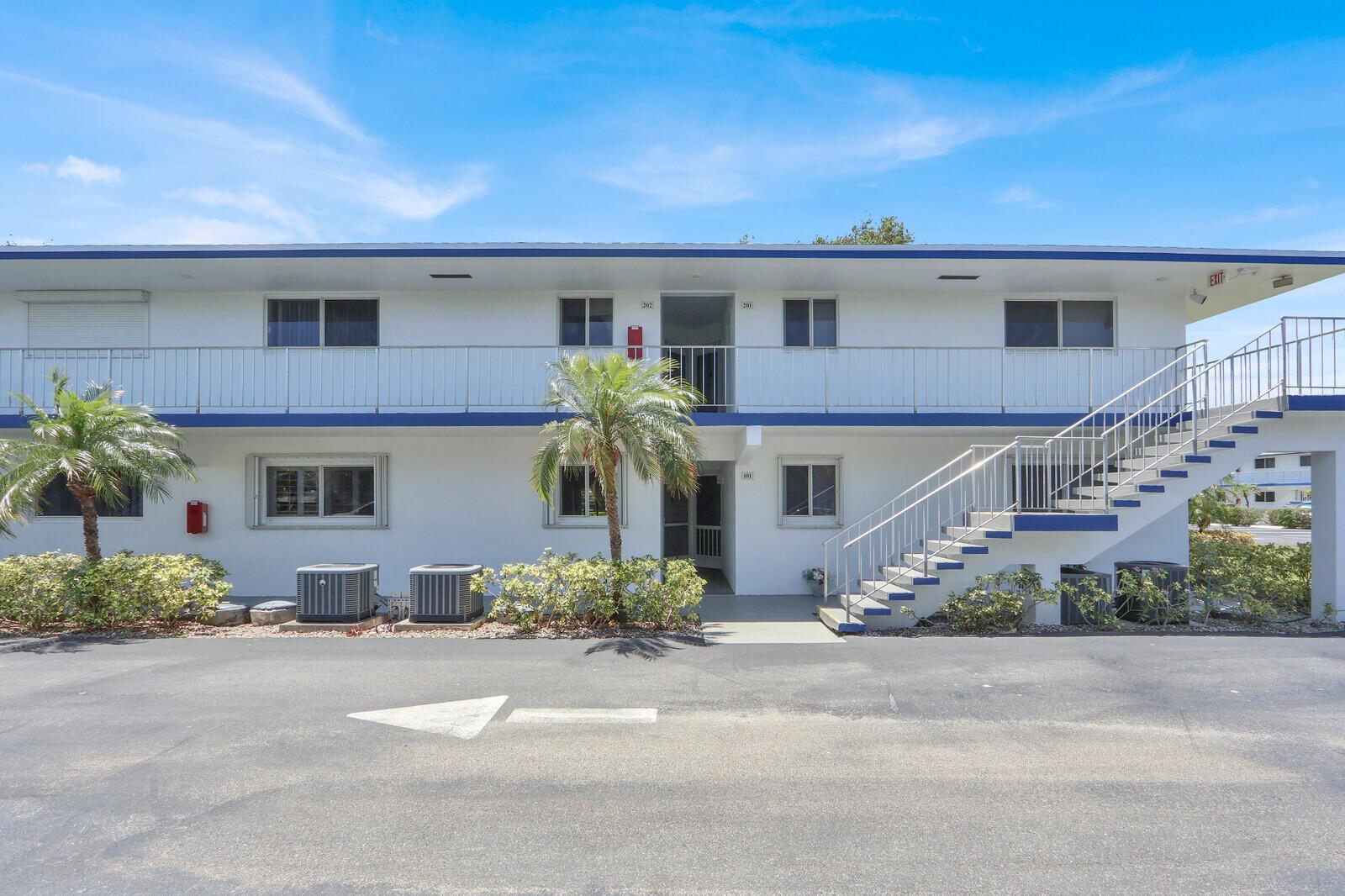 A two-story apartment building with white exterior walls, blue trim, and an outdoor staircase — 9 Westwood Avenue # 102b, Tequesta FL 33469, TEQUESTA, FL