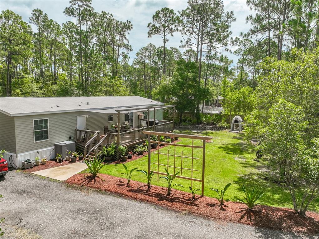 An elevated view of a manufactured home with a wooden deck and a backyard garden — 2553 GREENTREE STREET, BUNNELL, FL