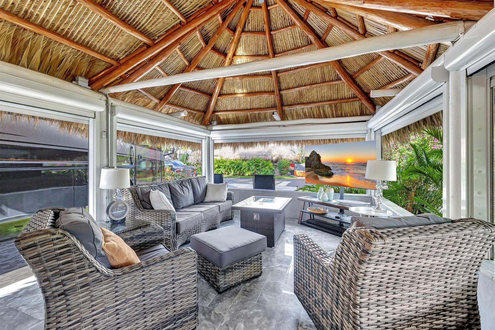 A covered outdoor living space with a thatched roof, wicker furniture, and a television — 58 S Carol Parkway # 58, Margate FL 33068, MARGATE, FL