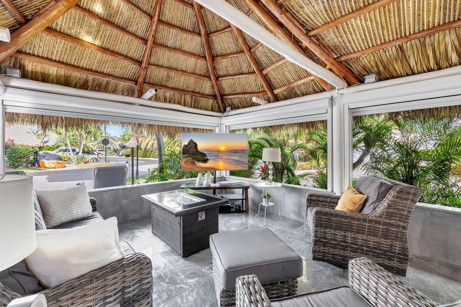 A covered outdoor patio features a thatched roof, wicker furniture, and a television — 58 S Carol Parkway # 58, Margate FL 33068, MARGATE, FL