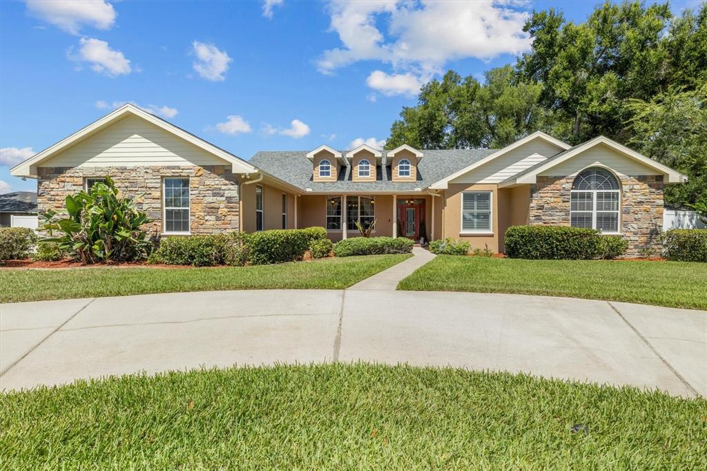 A single-story house with a stone facade, three dormer windows, and a concrete driveway — 615 N OAK AVENUE, FORT MEADE, FL