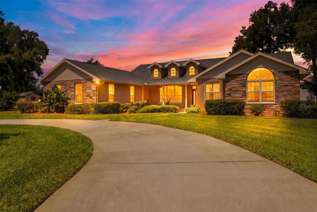 A single-story house with stone accents and a curved driveway at sunset — 615 N OAK AVENUE, FORT MEADE, FL