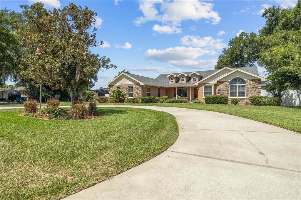 A single-story house with stone accents and a circular concrete driveway sits on a lawn — 615 N OAK AVENUE, FORT MEADE, FL