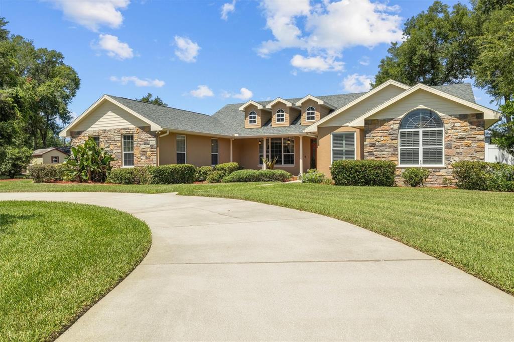 A single-story house with stone siding, a concrete driveway, and three dormer windows — 615 N OAK AVENUE, FORT MEADE, FL
