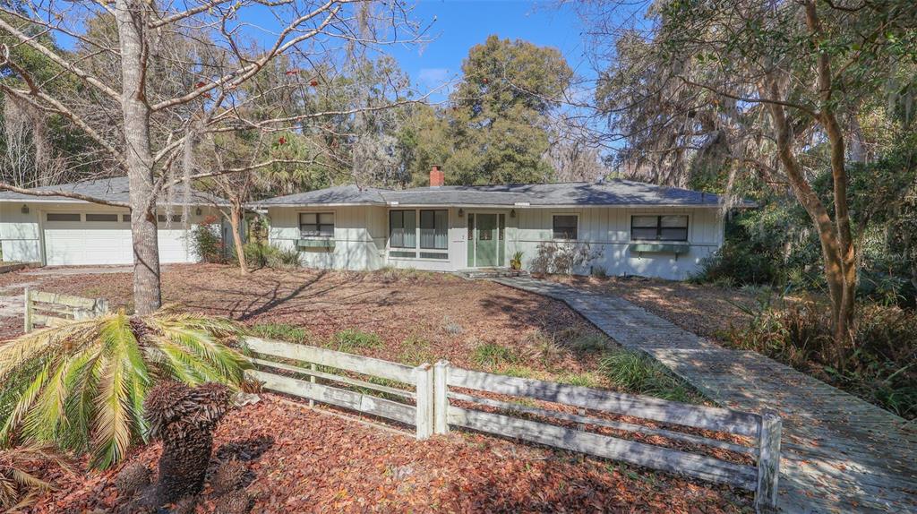 A single-story house with light siding, a detached garage, and a wooden walkway in front — 6116 TROUT STREET, MELROSE, FL