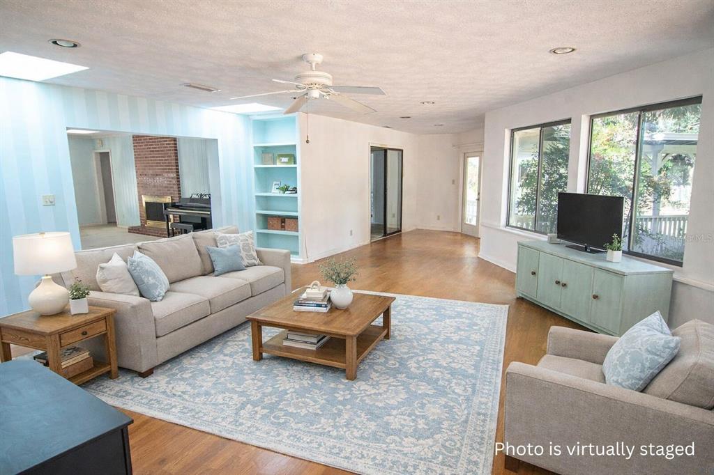 A virtually staged living room features a light blue area rug, sofa, and brick fireplace — 6116 TROUT STREET, MELROSE, FL