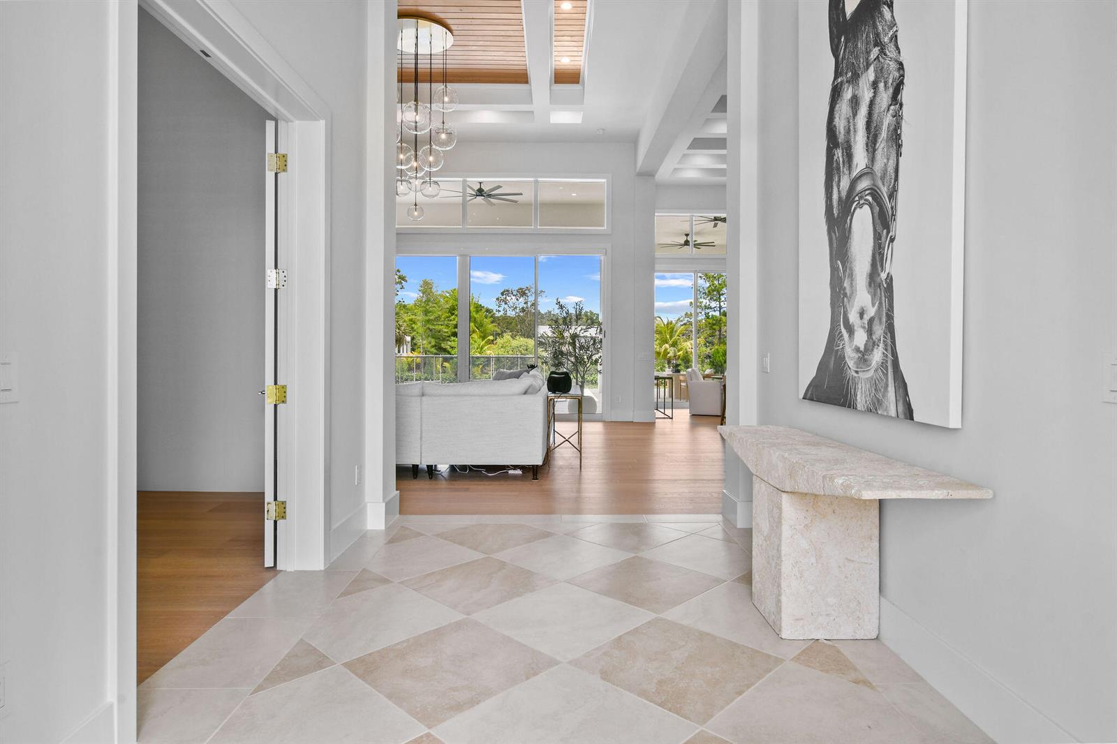 A bright entryway features a stone console table, horse artwork, and a checkered tile floor — 9105 Whippoorwill Trail, Jupiter FL 33478, JUPITER, FL