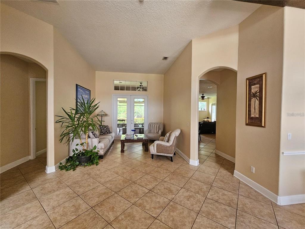 A living room features tile flooring, arched entryways, and a glass-paneled double door entrance — 6178 HEDGESPARROWS LANE, SANFORD, FL