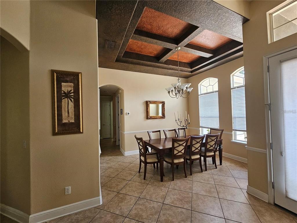 A dining room features a coffered ceiling, tile flooring, and a wooden table with chairs — 6178 HEDGESPARROWS LANE, SANFORD, FL