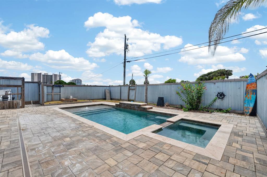 An outdoor swimming pool and spa with stone pavers enclosed by a metal fence — 2071 S PENINSULA DRIVE, DAYTONA BEACH, FL