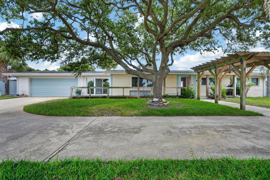 A single-story house with a large tree, a wooden pergola, and a concrete driveway — 2071 S PENINSULA DRIVE, DAYTONA BEACH, FL