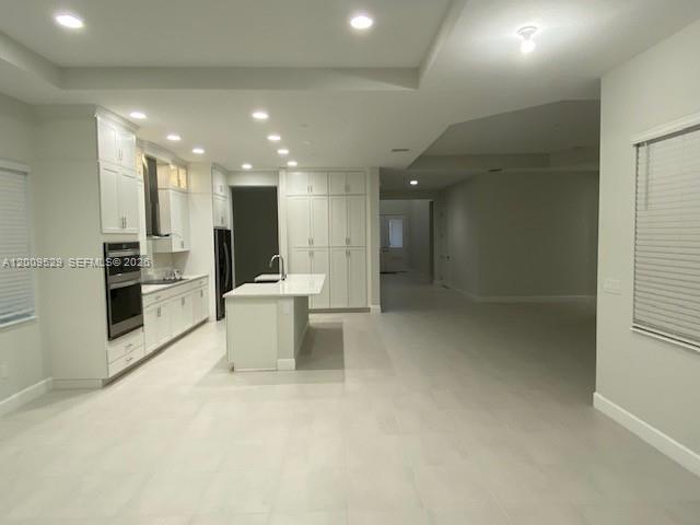 A modern kitchen features white cabinetry, a central island, and light-colored tile flooring — 4624 Citrus Blossom Ct, Westlake FL 33470, WESTLAKE, FL