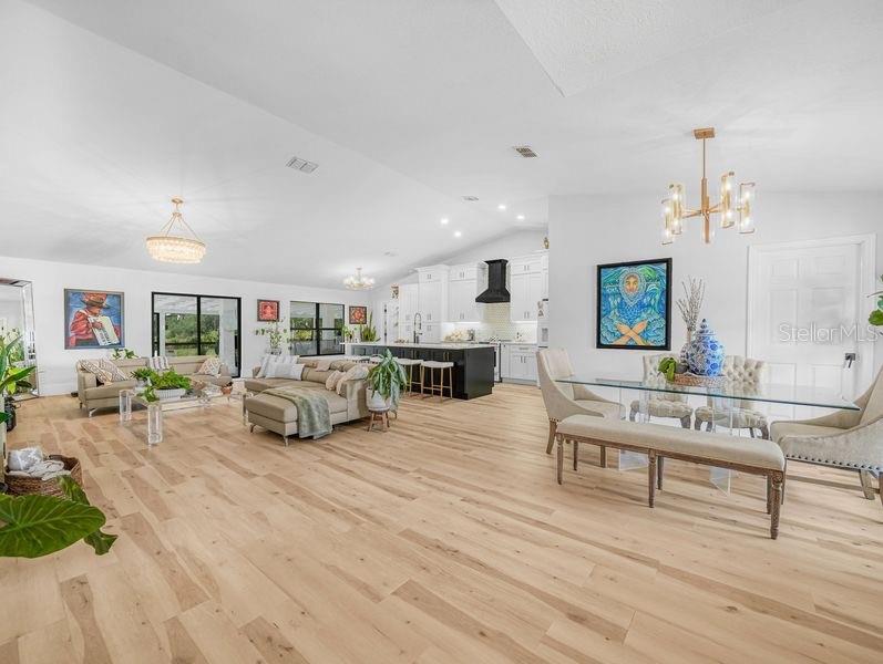 An open-concept living and dining area features light wood flooring, white cabinetry, and modern lighting — 1850 S LAKE REEDY BOULEVARD, FROSTPROOF, FL