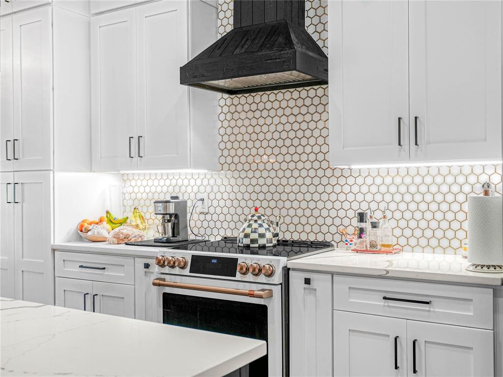 A kitchen features white cabinets, a black range hood, and a honeycomb tile backsplash — 1850 S LAKE REEDY BOULEVARD, FROSTPROOF, FL
