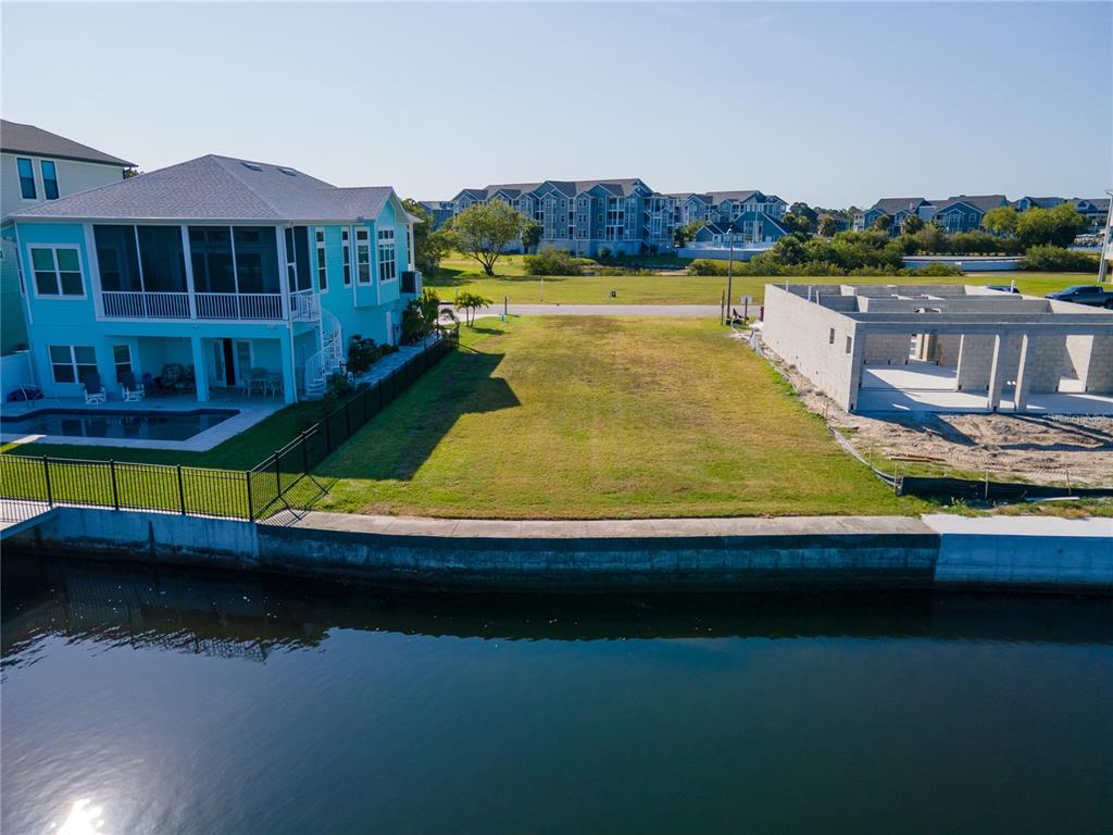 An aerial view shows a vacant waterfront lot situated between two houses — Lot 7 ELISABETHAN LANE, NEW PORT RICHEY, FL