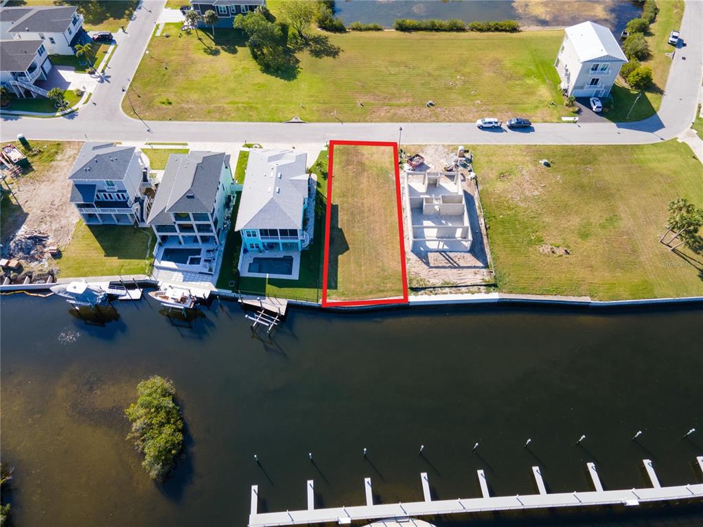 An aerial view shows a vacant waterfront lot outlined in red between two residential properties — Lot 7 ELISABETHAN LANE, NEW PORT RICHEY, FL