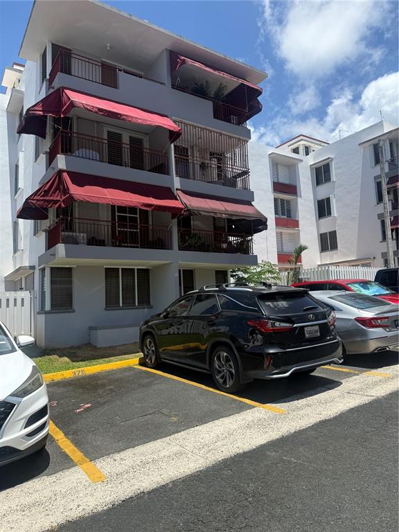 A multi-story apartment building with red awnings over balconies and parked cars in front — 1802 BOULEVARD DE LA MEDIA LUNA UNIT 1802, CAROLINA, PR