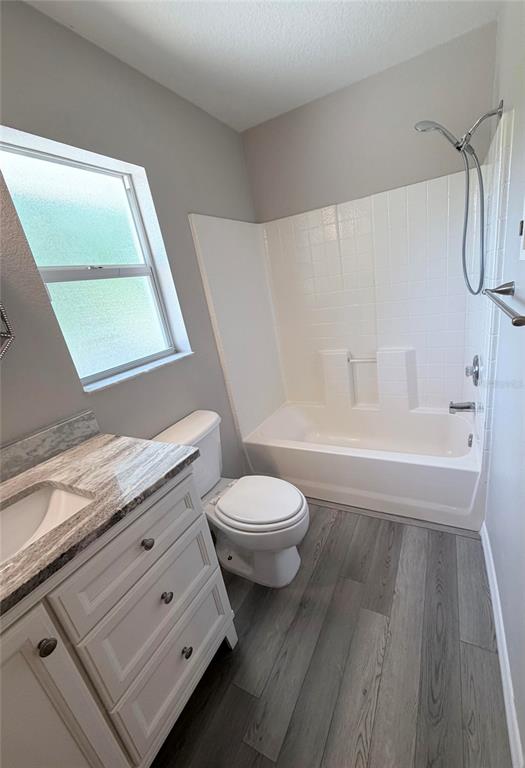 A bathroom features a vanity with a stone countertop, a toilet, and a shower-tub combo — 1088 NOMAD ROAD, PUNTA GORDA, FL