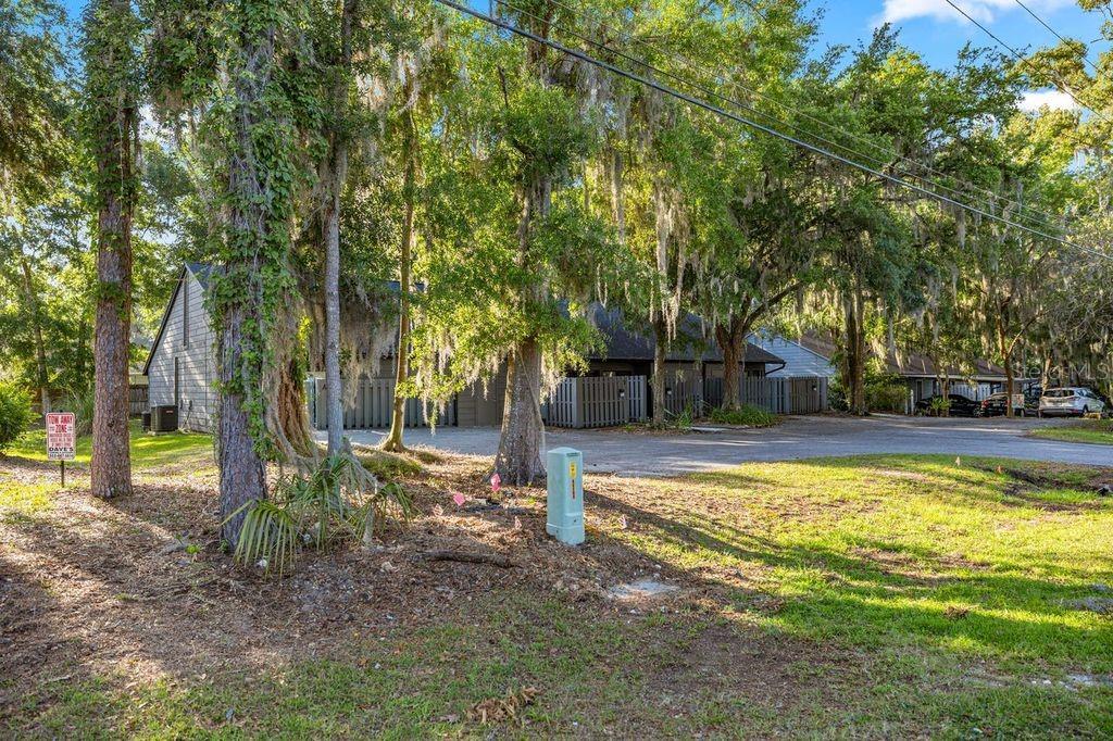 A view of a wooded parking area in front of residential buildings with gray siding — 4151 SE 22ND AVENUE, OCALA, FL