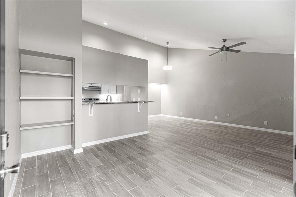 A living area with gray wood-look tile flooring, a ceiling fan, and built-in wall shelves — 4151 SE 22ND AVENUE, OCALA, FL