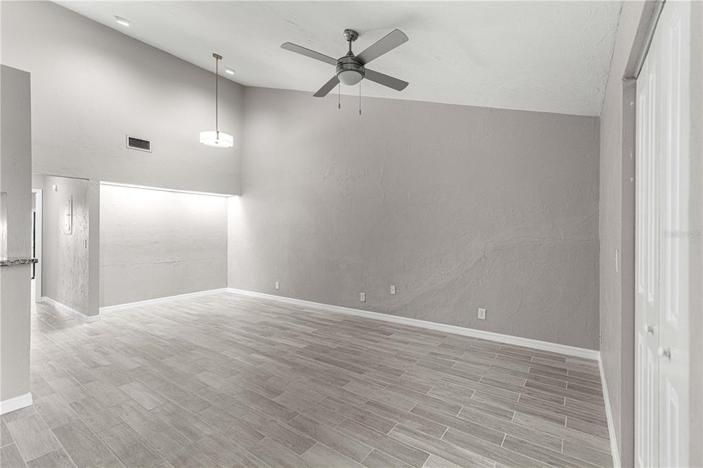 A spacious room with vaulted ceilings, a ceiling fan, and light gray wood-look tile flooring — 4151 SE 22ND AVENUE, OCALA, FL