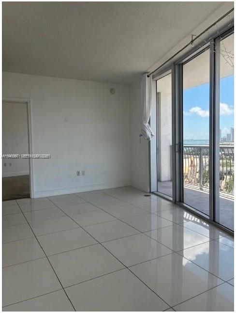 An empty room with white tile floors and large sliding glass doors overlooking the ocean — 1750 N Bayshore Dr # 1714, Miami FL 33132, MIAMI, FL