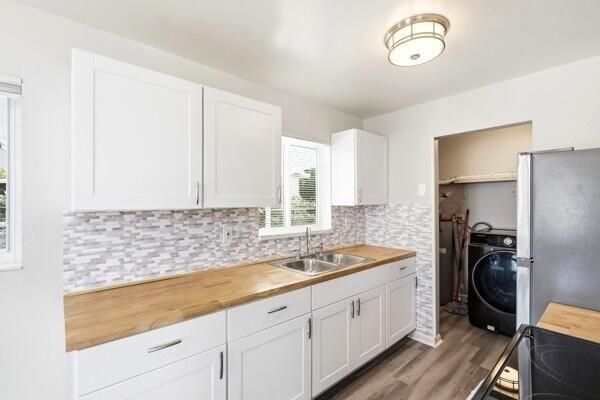 A kitchen features white cabinets, a wood countertop, a tile backsplash, and an adjacent laundry area — 2302 Avenue M, Riviera Beach FL 33404, RIVIERA BEACH, FL