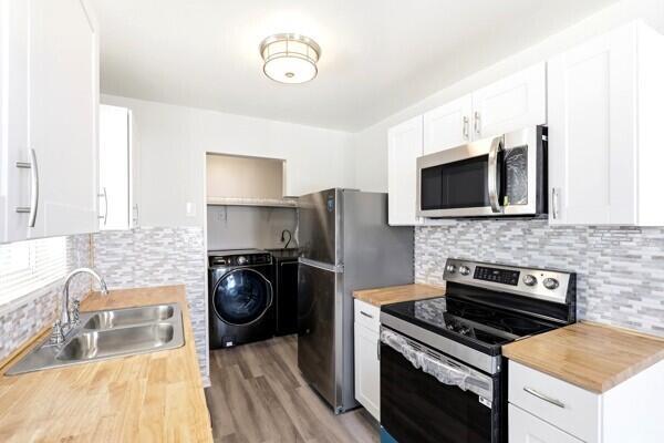 A kitchen with white cabinets, wood countertops, stainless steel appliances, and an adjacent laundry area — 2302 Avenue M, Riviera Beach FL 33404, RIVIERA BEACH, FL