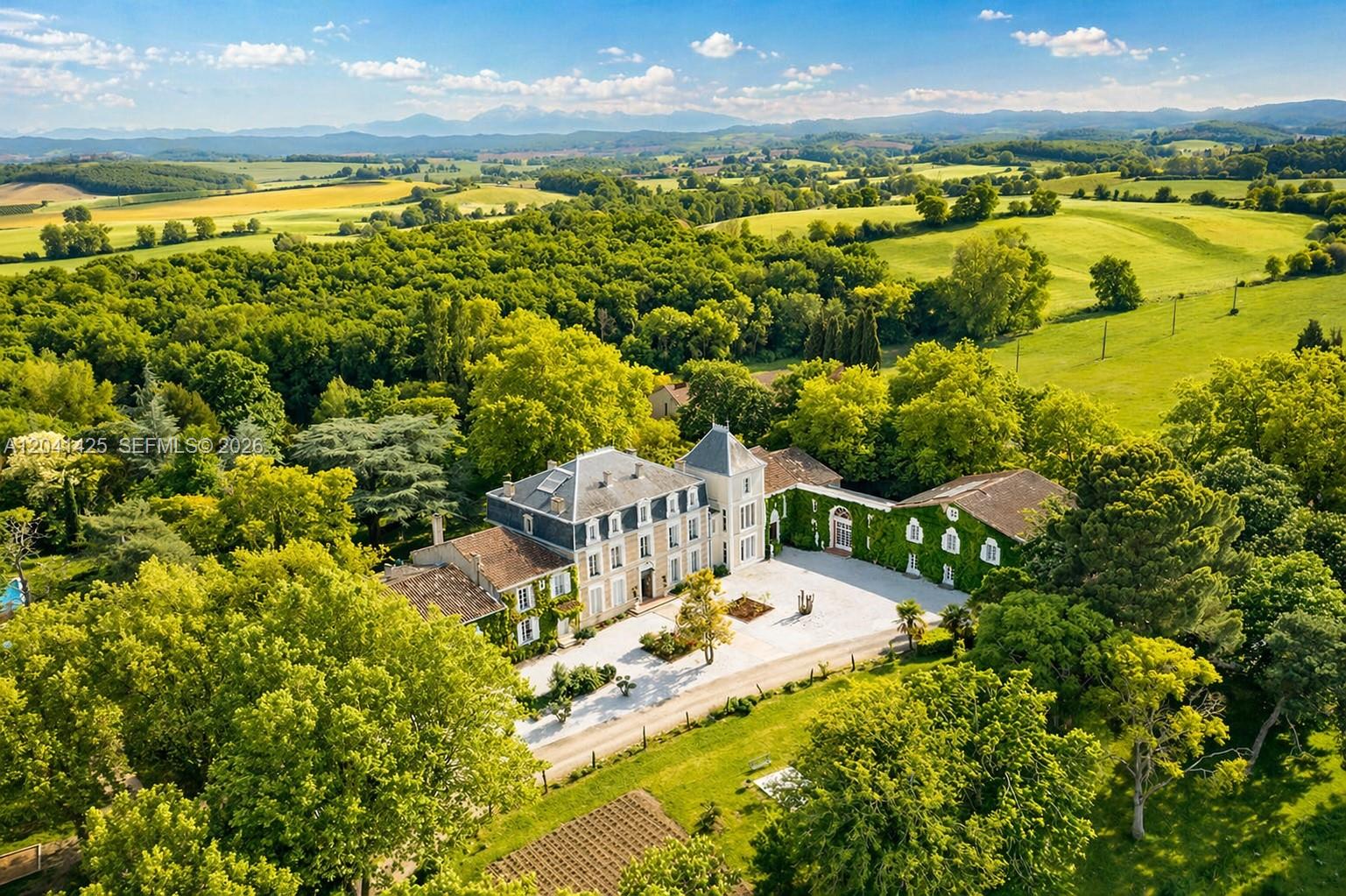 An aerial view of a large French chateau surrounded by lush trees and rolling fields — 1234 Mazerolles-du-Razès,, NY 11240, NY