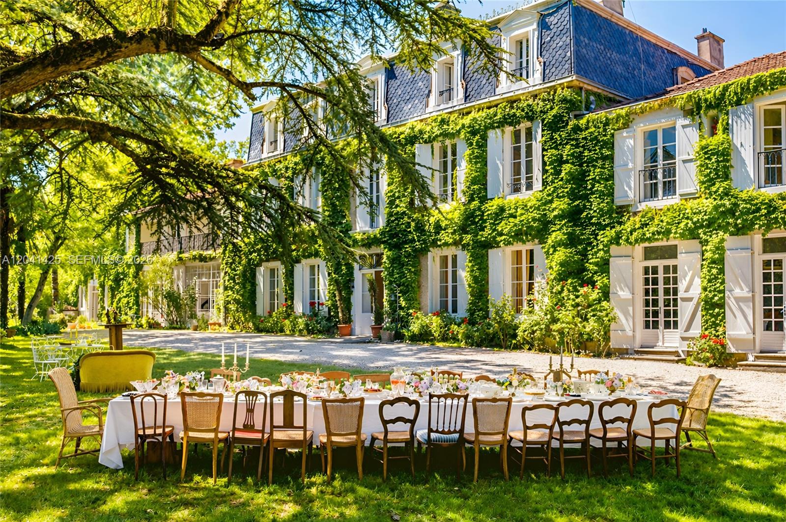 A long dining table is set on a lawn in front of a vine-covered mansion — 1234 Mazerolles-du-Razès,, NY 11240, NY