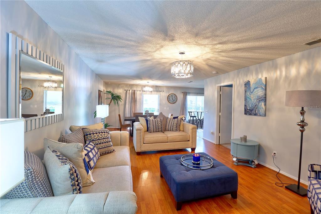 A living room features a blue ottoman, light-colored sofas, hardwood floors, and a ceiling light — 50989 HIGHWAY 27 UNIT 360, DAVENPORT, FL